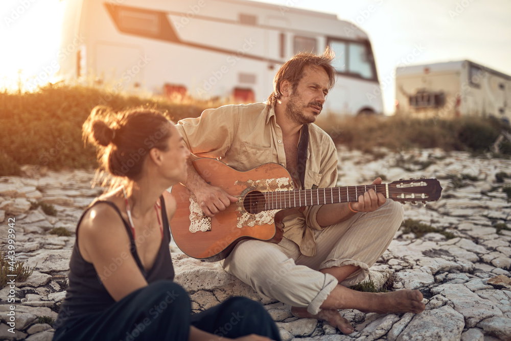 Man singing to his girlfriend on a beach.
