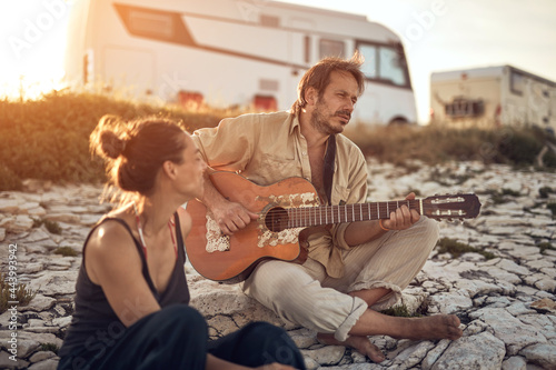 Man singing to his girlfriend on a beach.