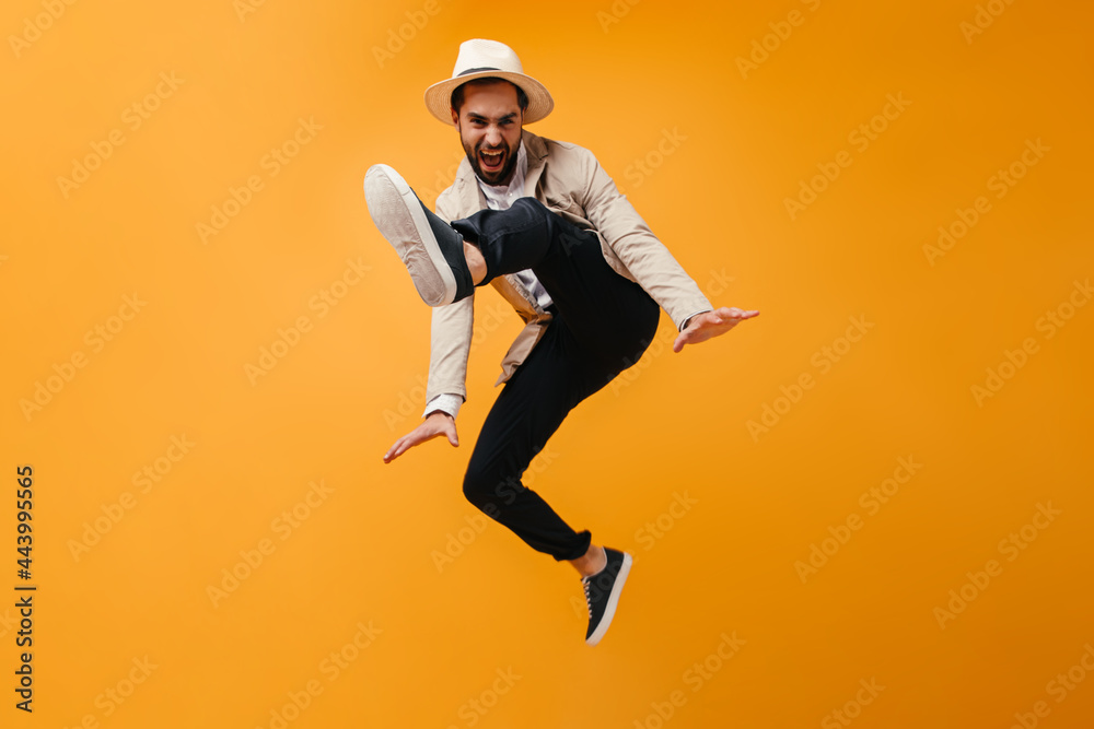 Funny man in hat jumps on orange background Funny man in hat jumps on orange background