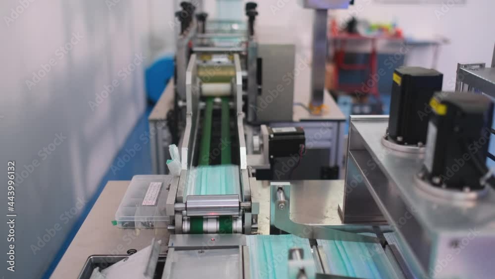 Close up line of hygiene mask producing machine is working to generate lots of product in workplace during virus pandemic and high demand of protective mask. Close up line of hygiene mask producing machine is working to generate lots of product in workplace during virus pandemic and high demand of protective mask.