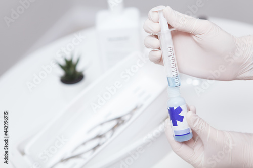 Close up of hands in gloves using syringe to prepare liquid disinfectant, copy space © Ihor