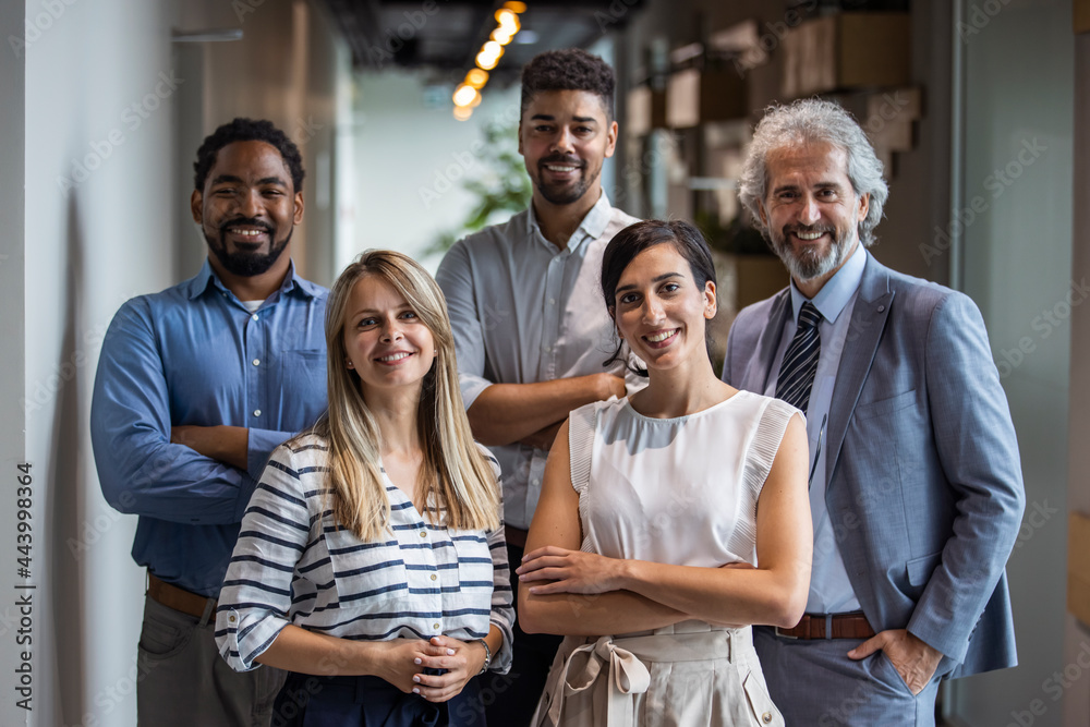 Shot of a group of well-dressed businesspeople standing together. Successful business team smiling teamwork corporate office colleague. Positive multi racial corporate team posing looking at camera