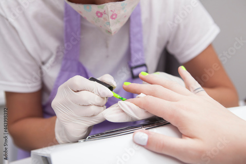 Close up of manicurist doing yellow neon nails for client