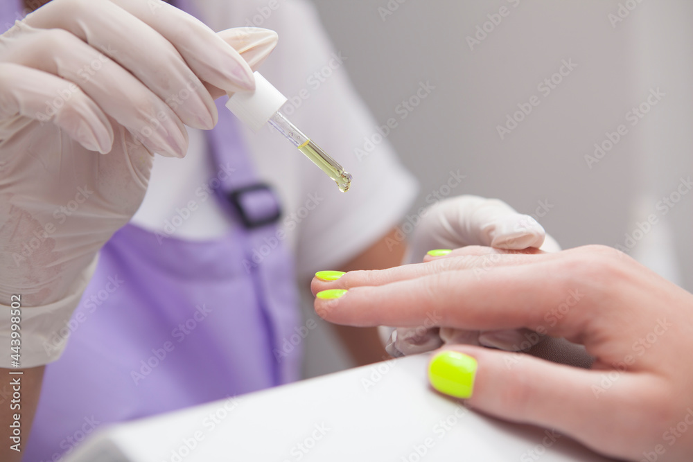 Close up of manicurist applying cuticle oil on hands of client Close up of manicurist applying cuticle oil on hands of client