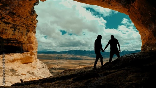 Couple inside cave against landscape. Romantic coupl Scenic rear view of a man and a woman walking in  outstanding caves against beautiful landscape in Cuevas de Zaen, Spain. Europe destinations.  photo