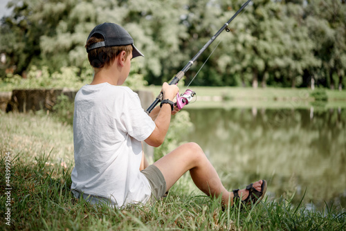 A boy holding a fishing rod and fishing in the lake, summer activities and hobbies for children