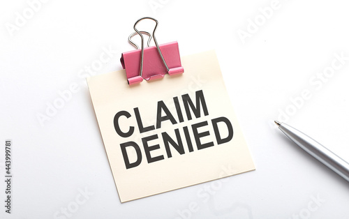 CLAIM DENIED text on sticker with pen on the white background