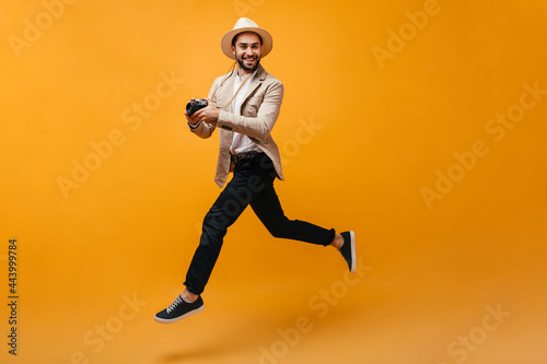 Cool man in dark pants and beige jacket jumps with camera © Look!
