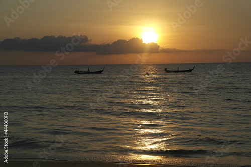 Tranquil bright sea sunset with the silhouette of two little boats on the water. Yellow Sun, boat, clouds. © Barashita_art