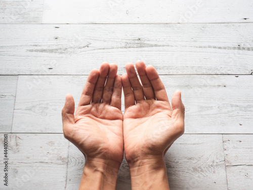 Closeup praying hands and sunlight nature shadow on wood table top view