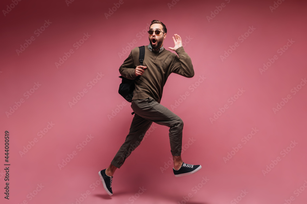 Man in brown outfit running on isolated background and holding backpack