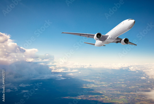 Commercial airplane flying above clouds on blue sky background