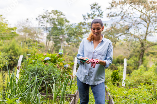 woman holding gardening tools in her hands in her vegetable garden