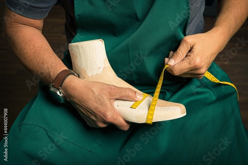 close-up of orthopedic shoemaker's hands doing quality control on a wooden last