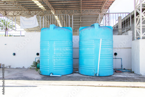 Blue plastic water tank storage system. At the park behind a large swimming pool to store water old and unusable