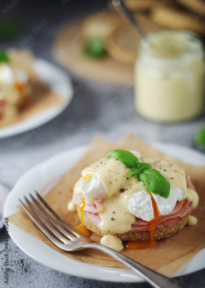Egg benedict sandwiches - muffin with poached egg, ham and hollandaise sauce Egg benedict sandwiches - muffin with poached egg, ham and hollandaise sauce