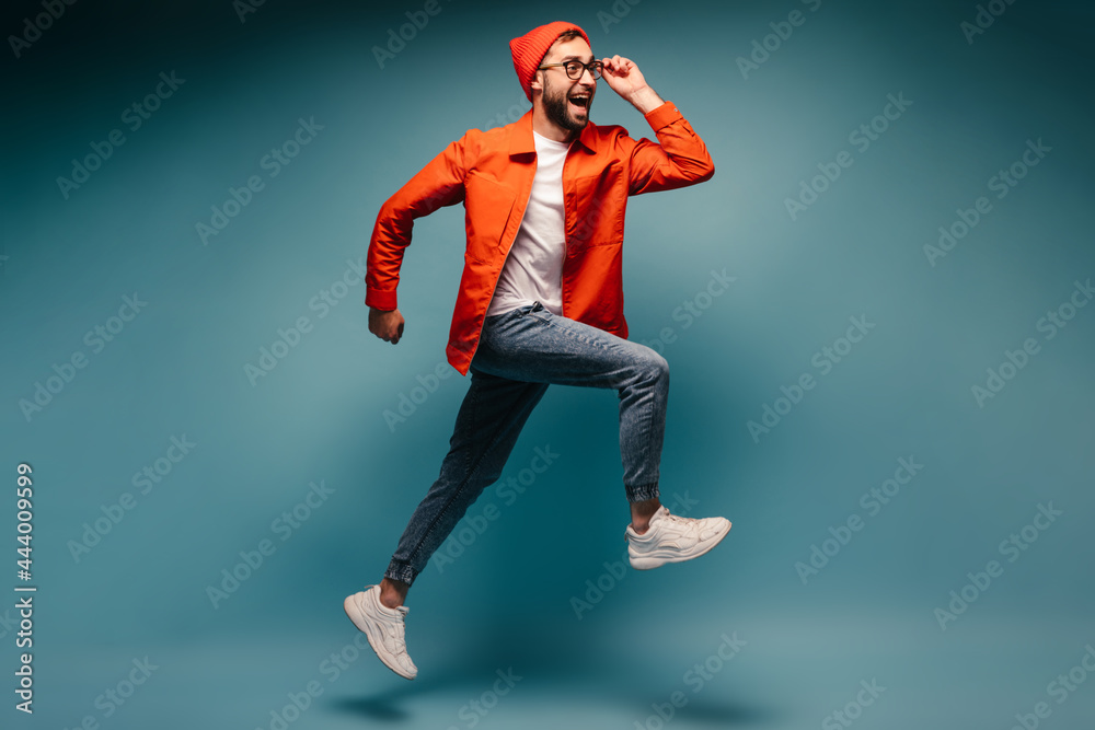 Young man happily running on blue background