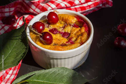 A portioned plate with clafoutis on a wooden background on a bright sunny day. Traditional French pie with cherry clafoutis. photo