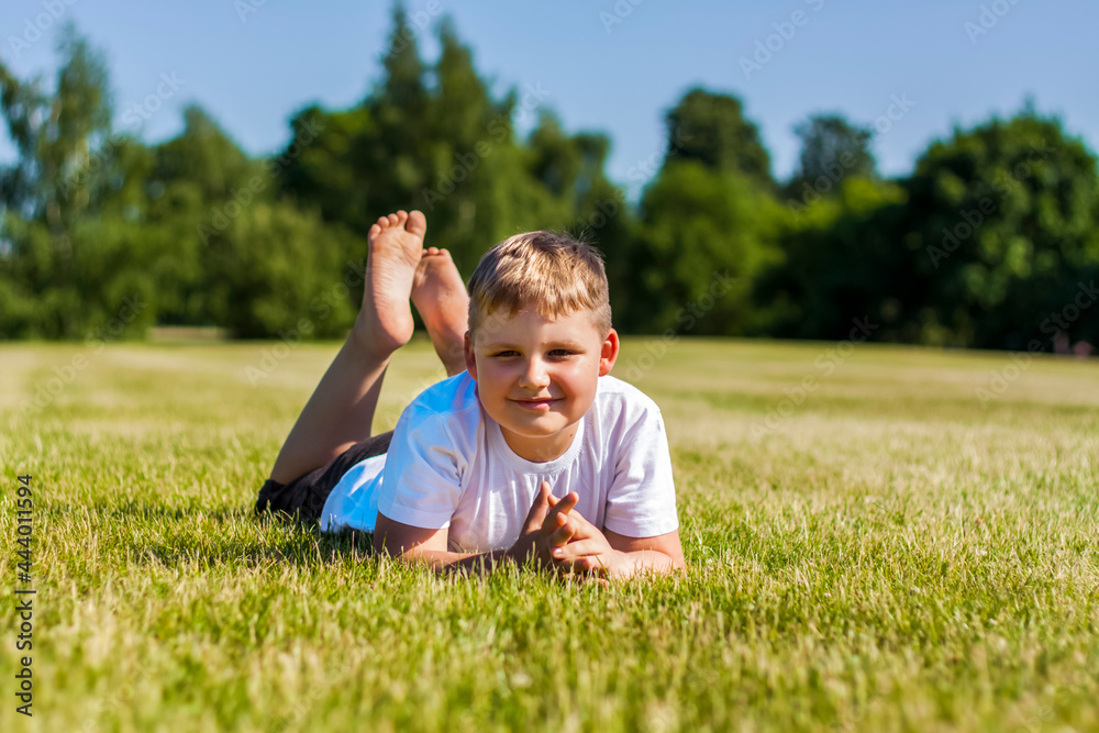 A cheerful child smiles with joy. I am happy to walk and play on the lawn in warm sunny weather in the park. the emotions of children on the face. A cheerful child smiles with joy. I am happy to walk and play on the lawn in warm sunny weather in the park. the emotions of children on the face.