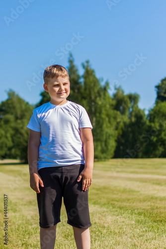 A cheerful child smiles with joy. I am happy to walk and play on the lawn in warm sunny weather in the park. the emotions of children on the face.