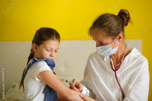 nurse in mask and white coat injects child girl with syringe  calling doctor at home  patronage. Treatment of pediatrician at home in real interior  concept of medicine and disease prevention