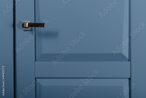 Modern chrome door handle on blue bright door
