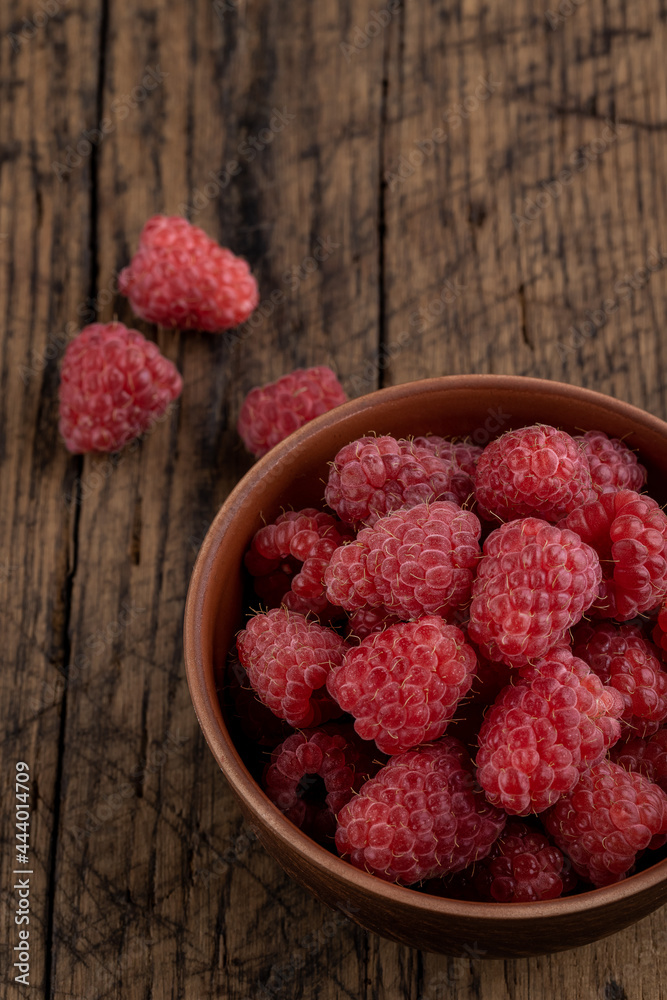 red fresh domestic raspberry at bowl on a rustic table top. space red fresh domestic raspberry at bowl on a rustic table top. space