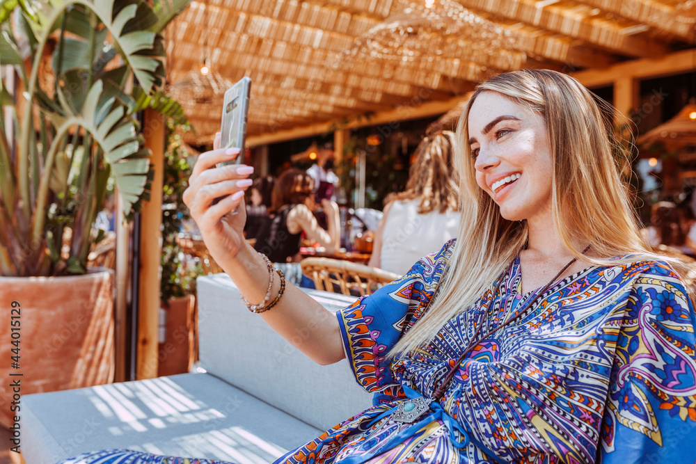 Obraz premium Beautiful smiling latin woman taking selfie with smartphone at terrace