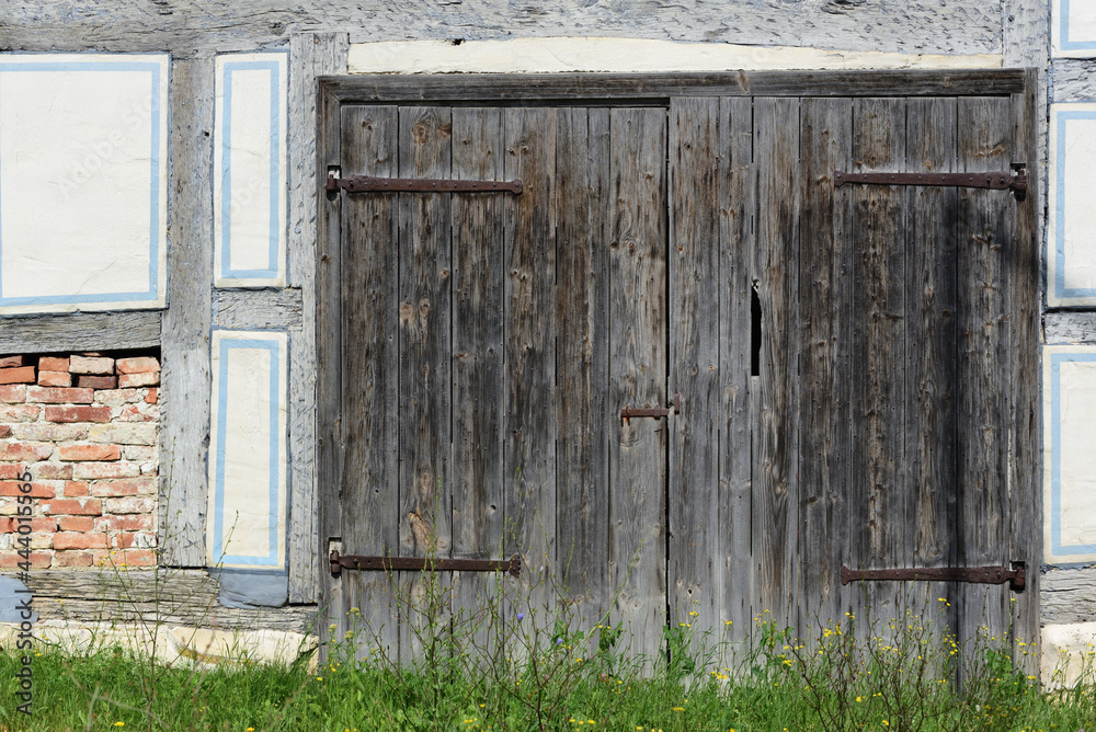 Close-up and detailed shot of an old historical facade of a traditional half-timbered house, with blue painted wood and white plaster and a wooden door Close-up and detailed shot of an old historical facade of a traditional half-timbered house, with blue painted wood and white plaster and a wooden door