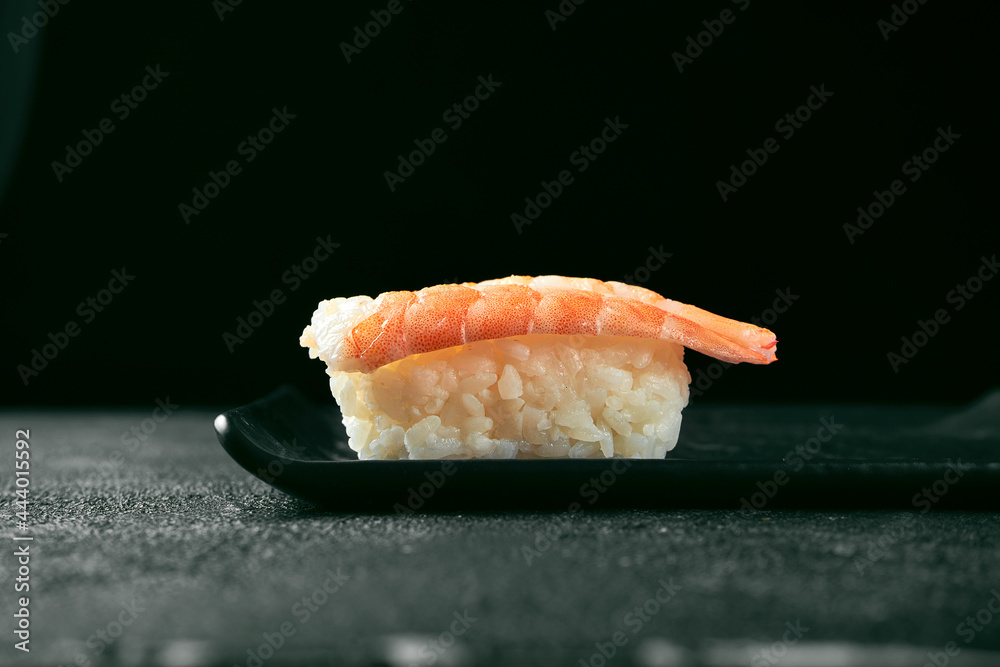 Nigiri sushi with shrimp on a black board. Japanese kitchen. Food delivery. Black background Nigiri sushi with shrimp on a black board. Japanese kitchen. Food delivery. Black background
