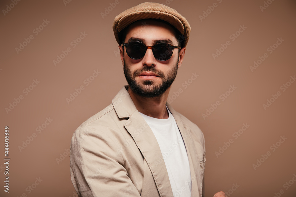 Portrait of man wearing beige jacket, cap and sunglasses on isolated background Portrait of man wearing beige jacket, cap and sunglasses on isolated background
