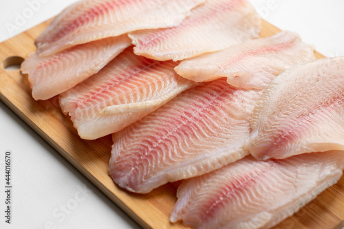pieces of raw fish, tilapia on a wooden surface. Fresh fish, seafood, vitamins, d3. The benefits or harms of seafood, deficiency