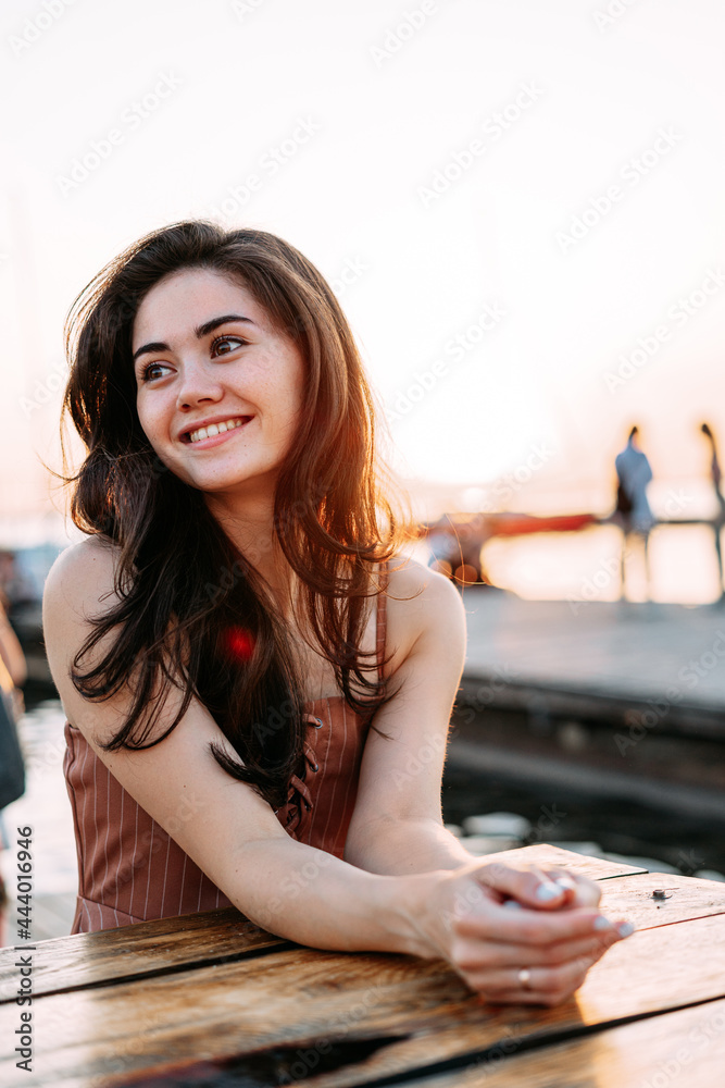 young beautiful smiling woman sits at a wooden table young beautiful smiling woman sits at a wooden table
