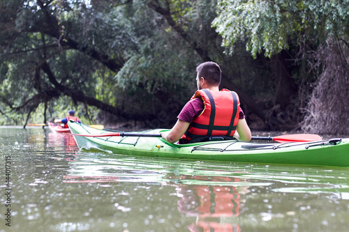 People kayaking in wild Danube river and lake on biosphere reserve in spring