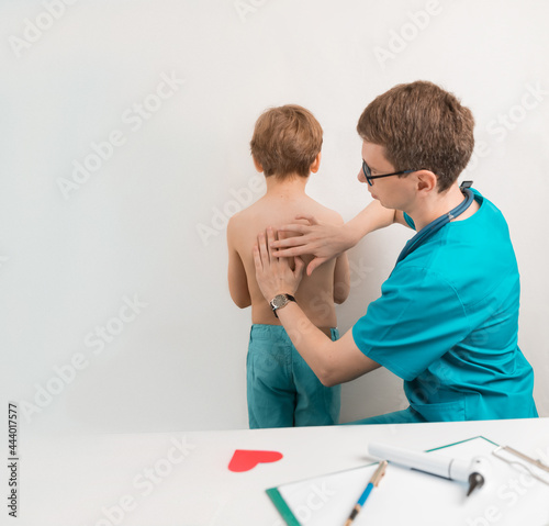 The children's doctor performs percussion of the lungs and heart in the child at the examination. Tapping the lungs. pneumonia in children, risk of coronavirus in adolescents, copyspace photo