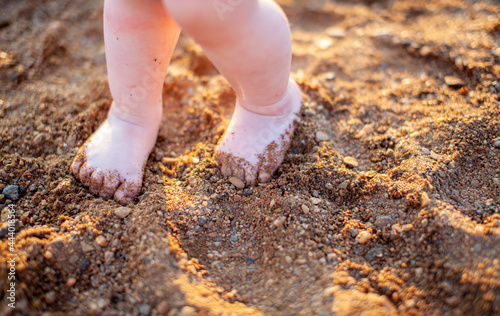 Children's bare feet in summer on a golden sandy beach close-up. The concept of child safety. The concept of recreation with children.