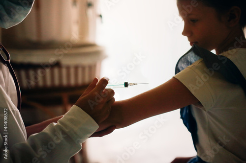 nurse in mask and white coat injects child girl with syringe, calling doctor at home, patronage. Treatment of pediatrician at home in real interior, the concept of medicine and disease prevention