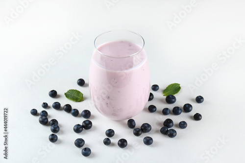 Studio shot of one blueberry milkshake glass. Single protein shake drink with berries isolated on white background. Clean eating concept. Copy space for text, close up, top view