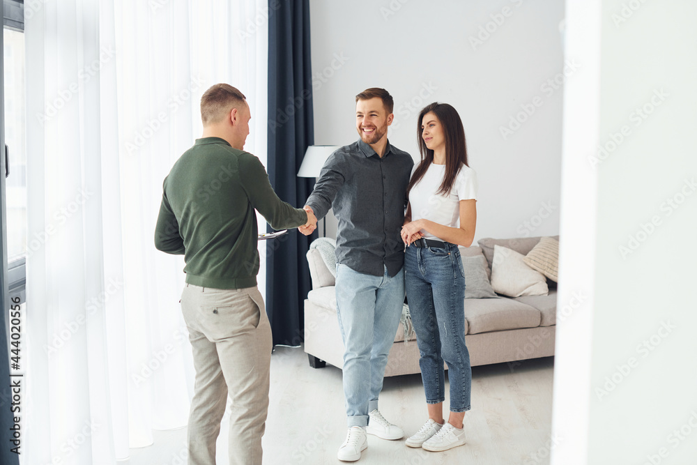 Salesman helps young couple in choosing an apartment. Conception of business and rent Salesman helps young couple in choosing an apartment. Conception of business and rent