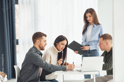 Four people works in the office by sitting by the table indoors