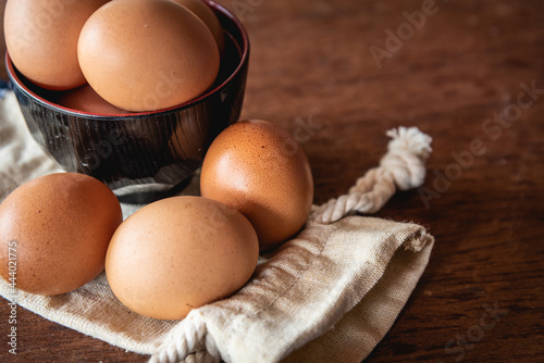 Eggs in the little bowl on the white cloth bag as wooden background for cooking with new recipe