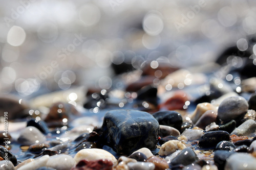 Fototapeta Naklejka Na Ścianę i Meble -  Wet pebble stones on blurred background of sea waves. Summer vacation concept
