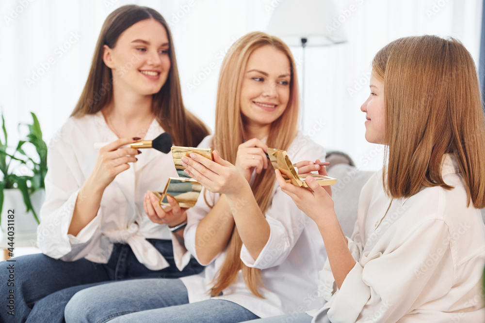 Teaching how to do make up. Young mother with her two daughters at home at daytime Teaching how to do make up. Young mother with her two daughters at home at daytime
