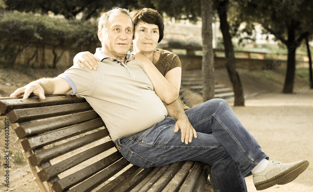 middleaged male and female posing on bench middleaged male and female posing on bench