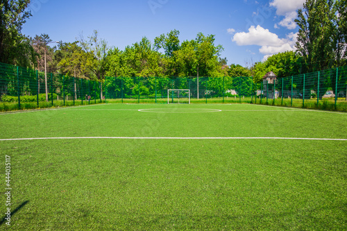 Soccer field with artificial green grass near the school. Amateur football field. Sunny summer day