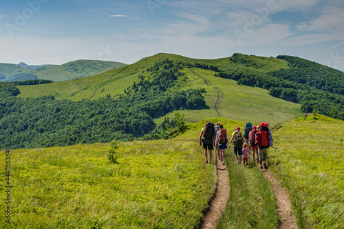 A group of tourists with large backpacks is walking along the beautiful water-producing ridge in the Carpathians. Ukraine