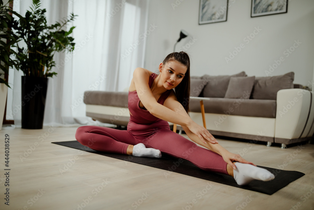Athletic woman in sportswear doing fitness stretching exercises at home in the living room. Athletic woman in sportswear doing fitness stretching exercises at home in the living room.