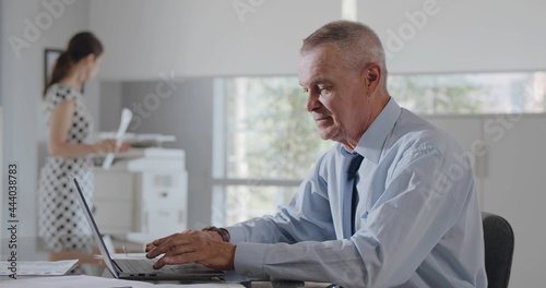 Medium shot of mature business manager working in office on laptop