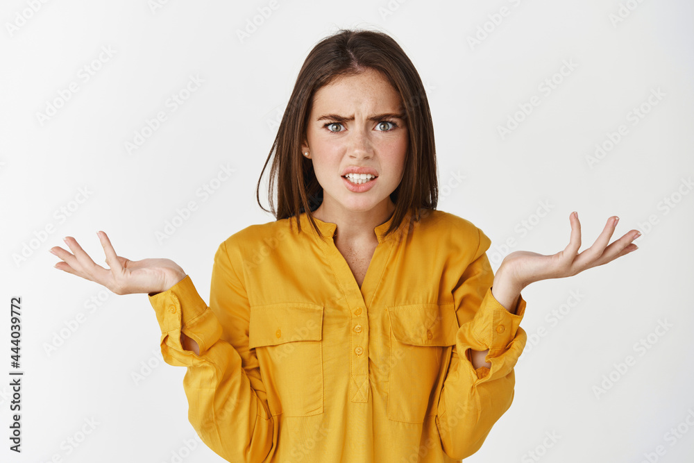 Confused and nervous woman asking what, spread hands sideways and staring at camera puzzled, cant understand whats happening, standing over white background Confused and nervous woman asking what, spread hands sideways and staring at camera puzzled, cant understand whats happening, standing over white background
