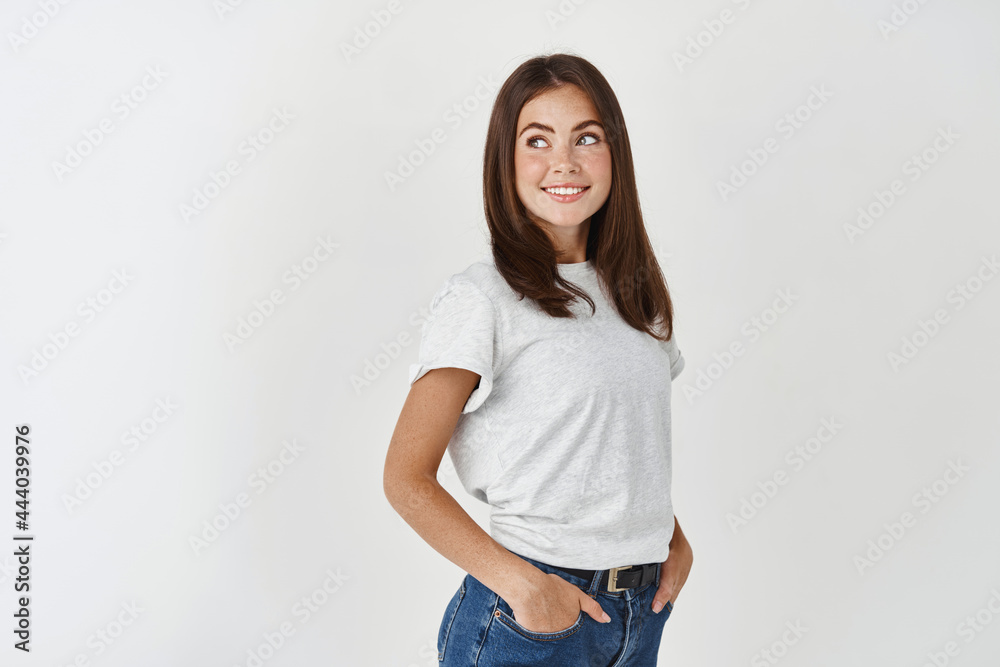 Profile of young ambitious woman looking left with interest, standing over white background Profile of young ambitious woman looking left with interest, standing over white background